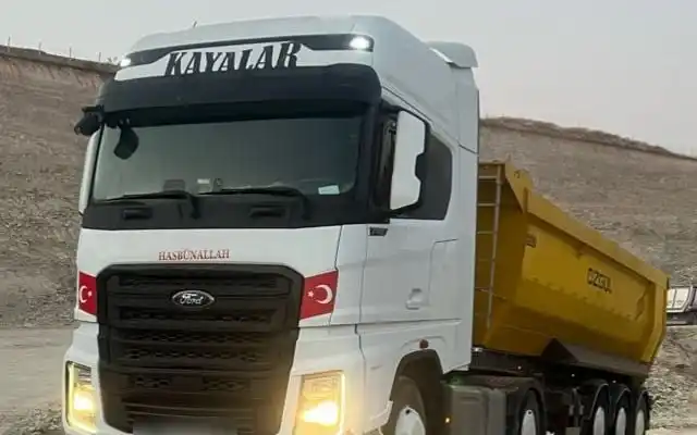 Ön camında KAYALAR yazan beyaz Ford çekici ve sarı damperli dorse