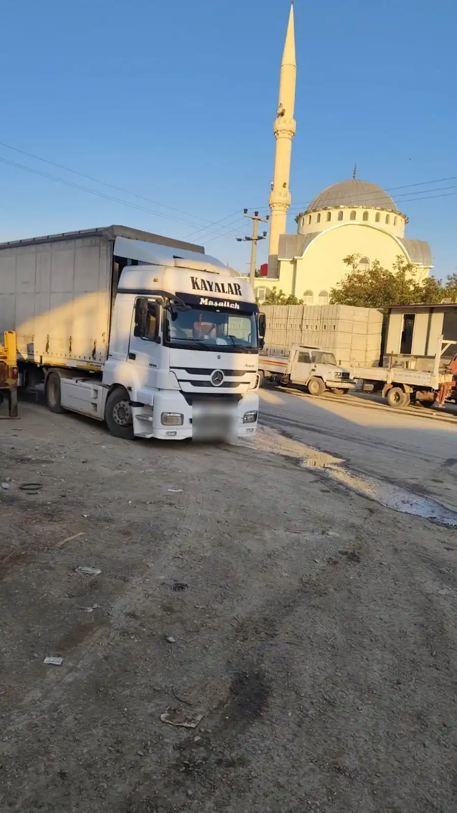 Ön camında KAYALAR yazan beyaz Mercedes çekici, arkasında cami
