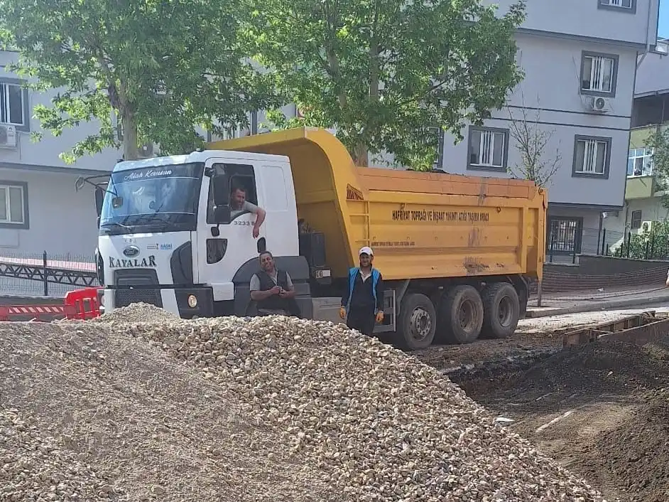 Ön tamponunda KAYALAR yazan sarı kasalı kırkayak, şantiyeye boşaltılmış mıcır yığınının arkasında