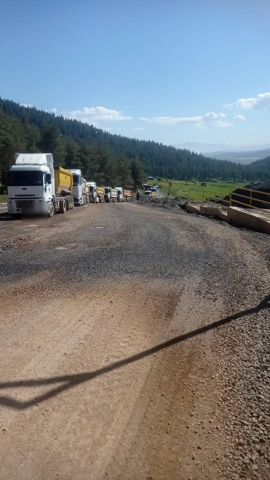 Yol çalışmasında arka arkaya sıralanmış damperli tırlar ve serilmiş malzeme