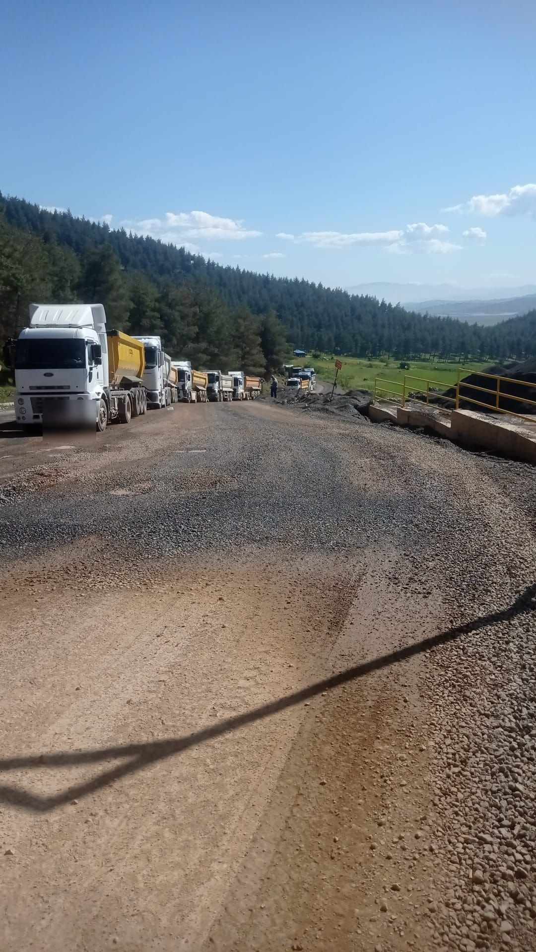 Yol çalışmasında arka arkaya sıralanmış damperli tırlar ve serilmiş malzeme